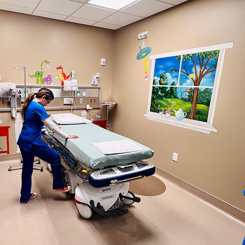 Preparing for her first patient, Jennifer Madrona, BSN, RN adjusts the bed in a colorful pediatric specialty room at HCA Houston ER 24/7 Fallbrook. 